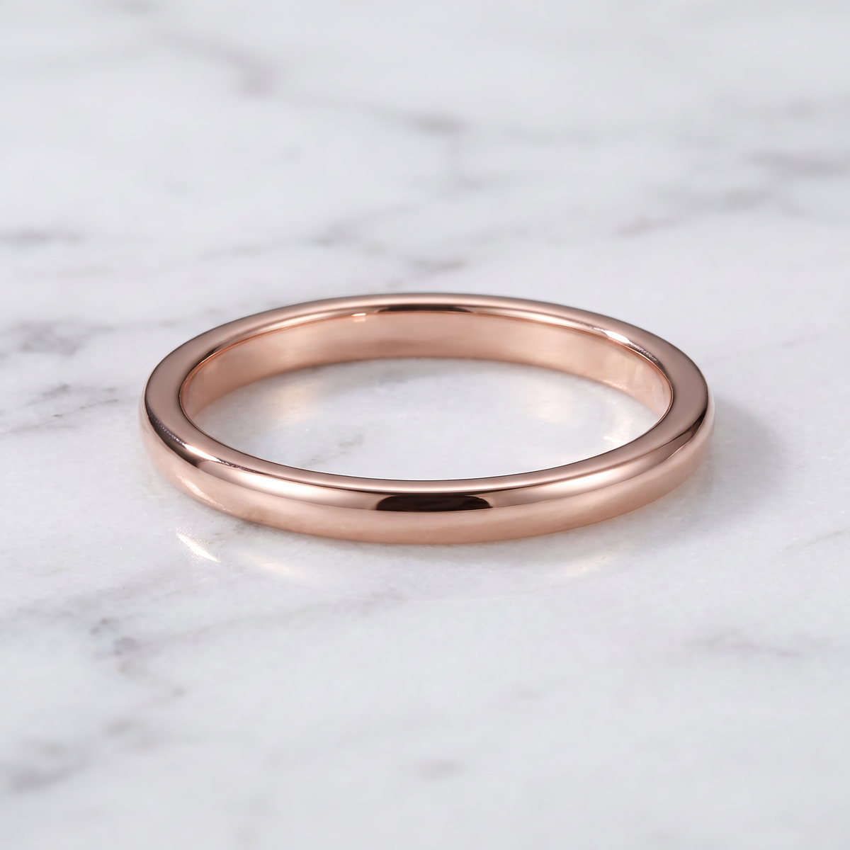 The Filament rose color tungsten ring lying flat on white marble
