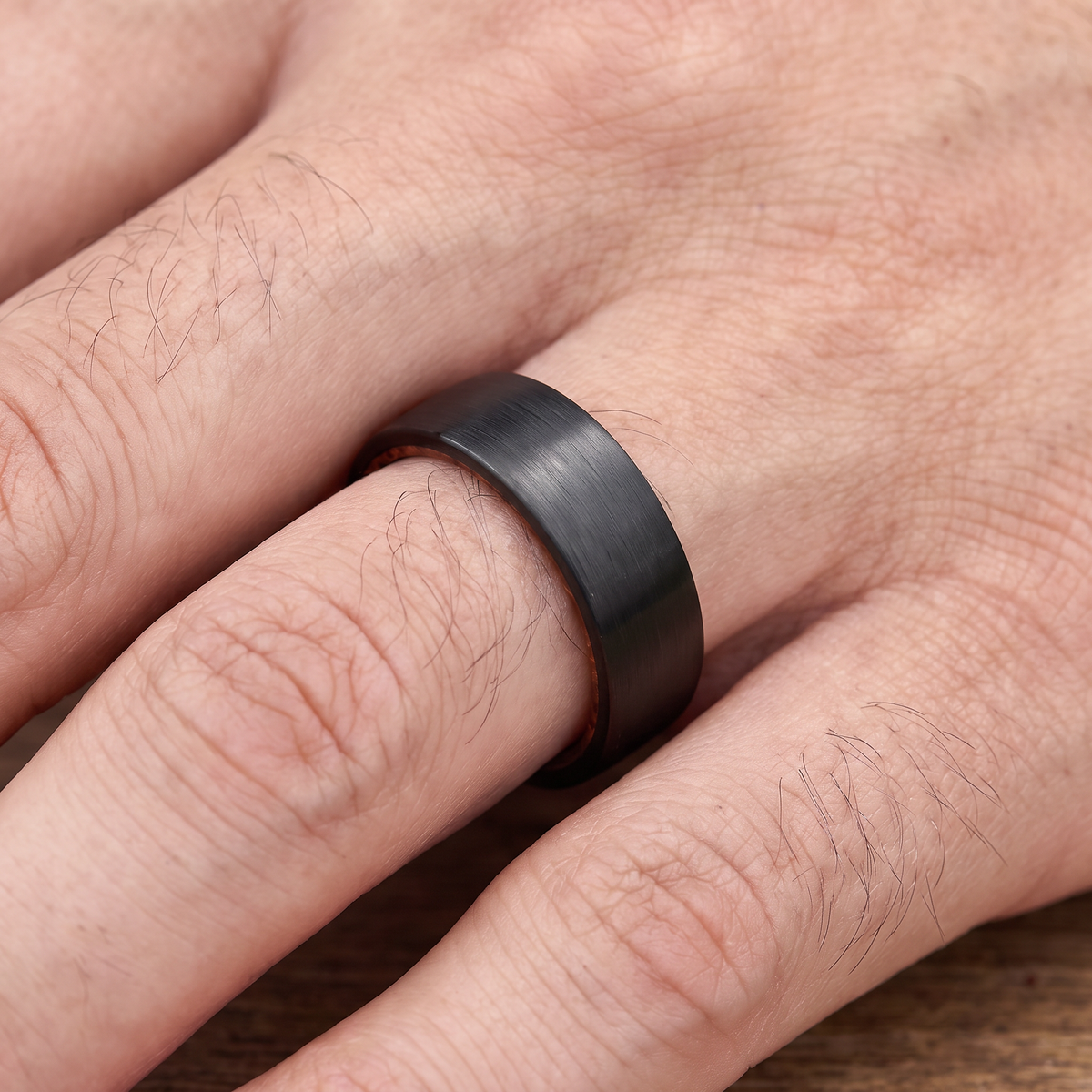 Close up of a man's hand wearing The Ember black brushed tungsten ring