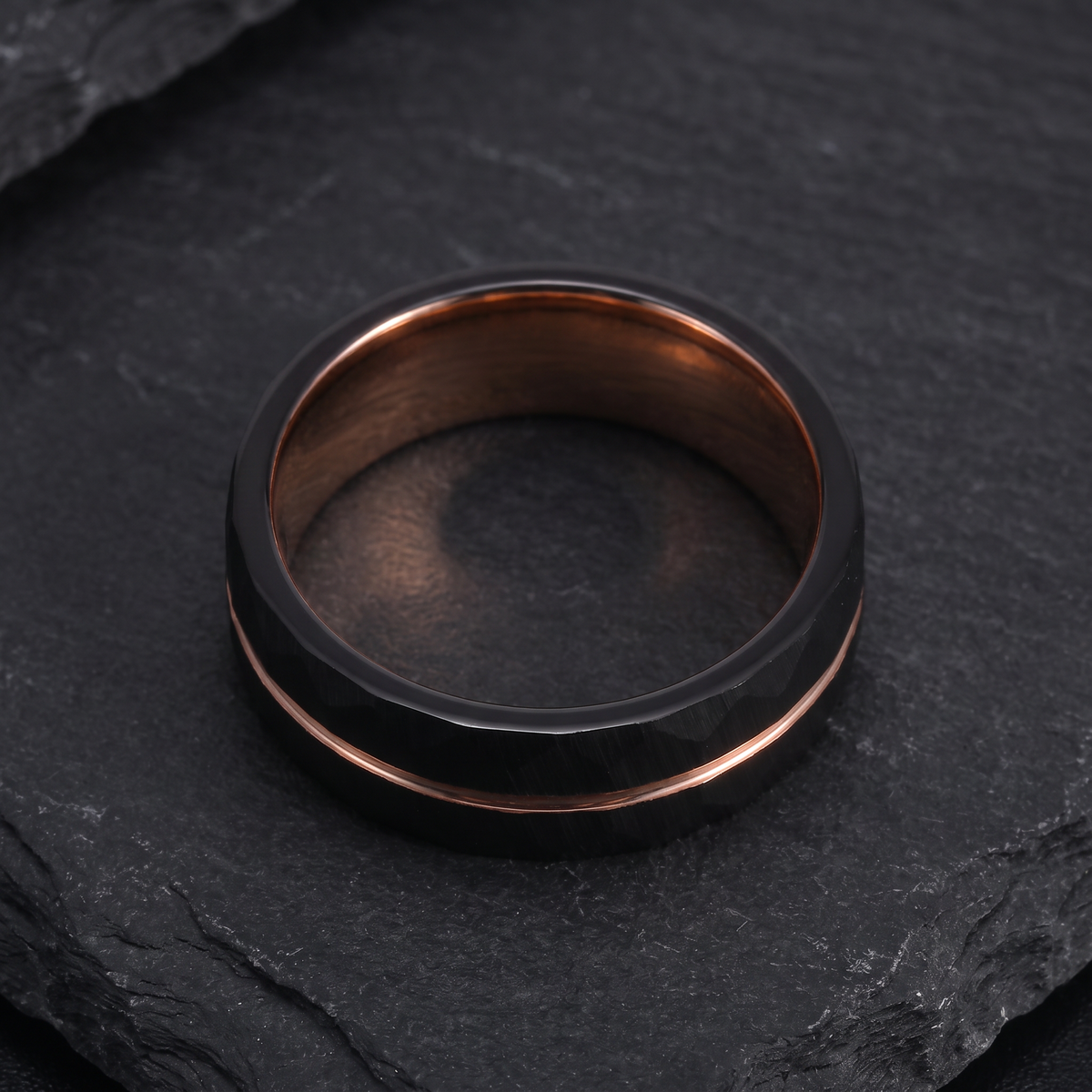 The Daybreak tungsten ring lying flat on dark slate showing the rose gold interior