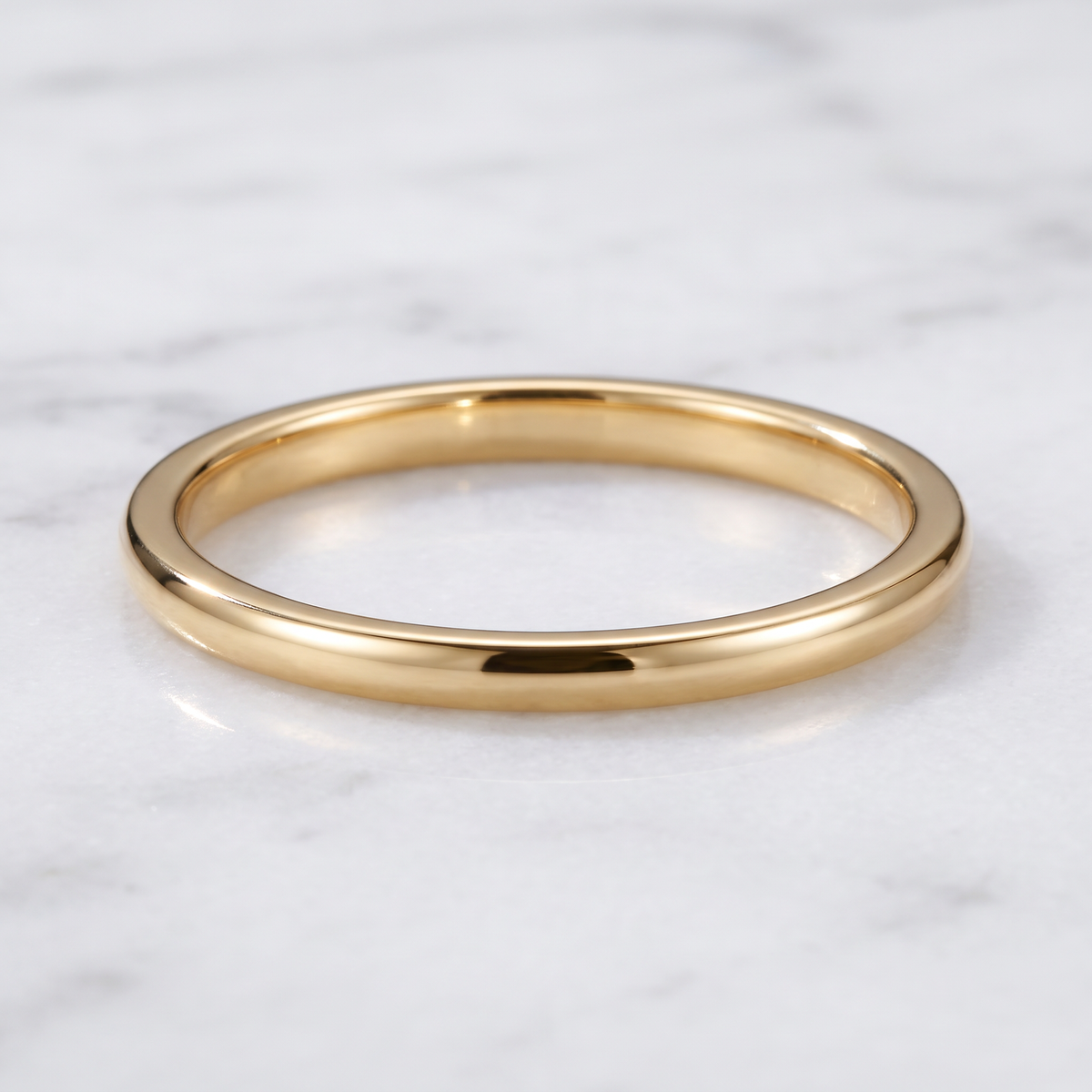 The Filament gold color tungsten ring lying flat on white marble