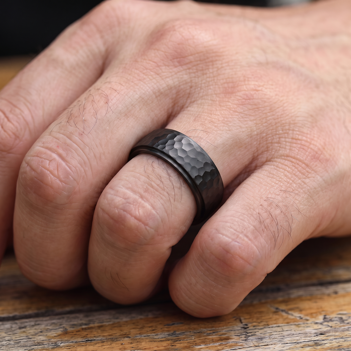 Close up of a man's hand wearing The Crater black hammered ring