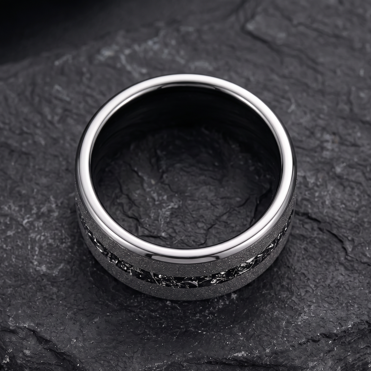 The Shard tungsten ring with a crushed zircon inlay lying flat on dark slate