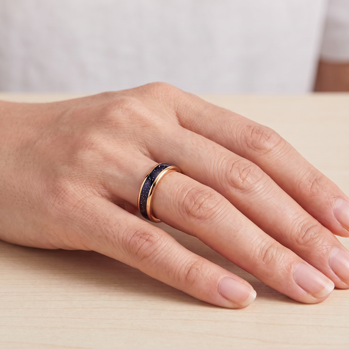 Close up of a woman's hand wearing The Vega rose color tungsten ring with a galaxy opal inlay