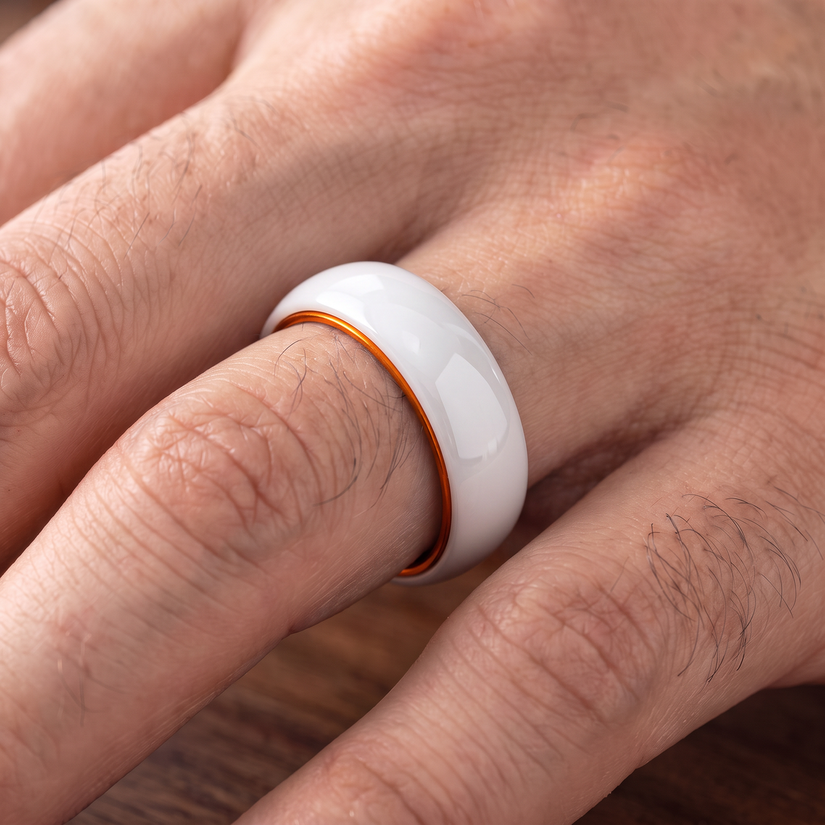 The Prism white ceramic ring with orange interior worn on a hand