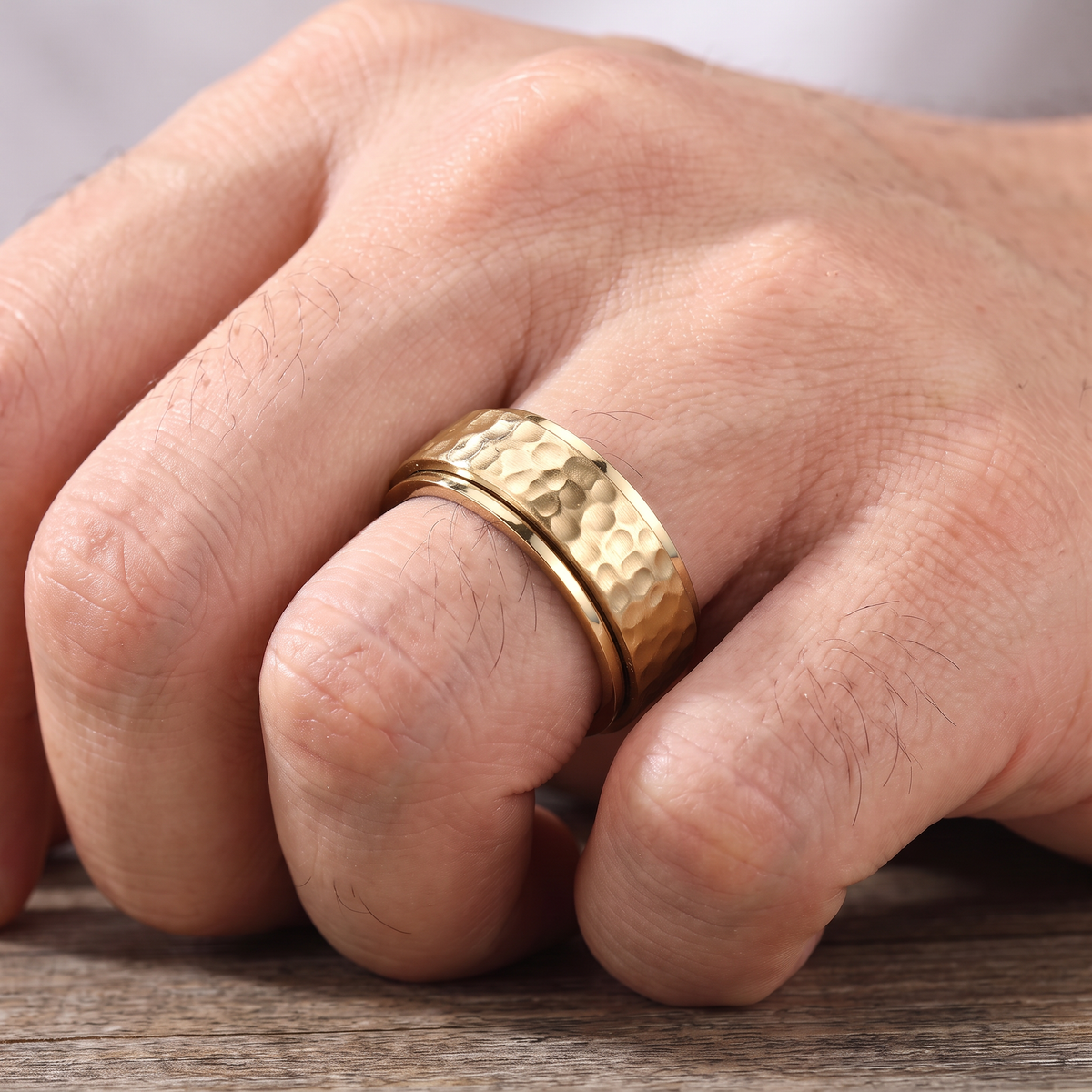 Close up of a man's hand wearing The Orbit gold spinner ring