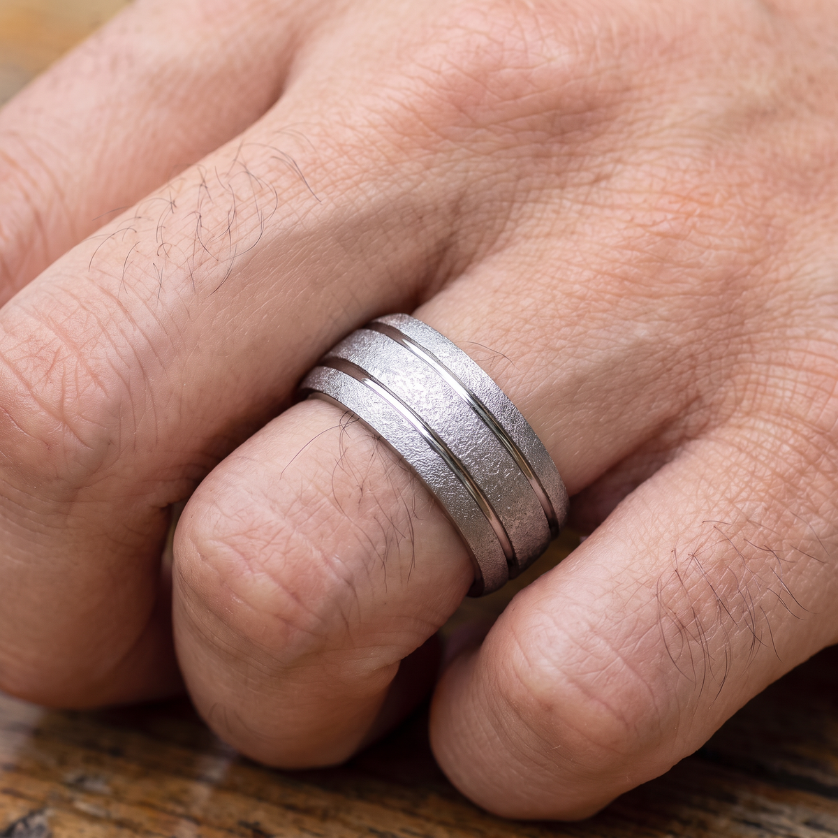 Close up of a man's hand wearing The Granite silver sandblasted tungsten ring