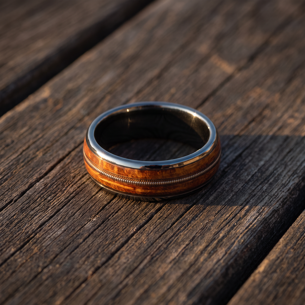 The Roadhouse tungsten ring lying flat on weathered oak wood showing the gray interior