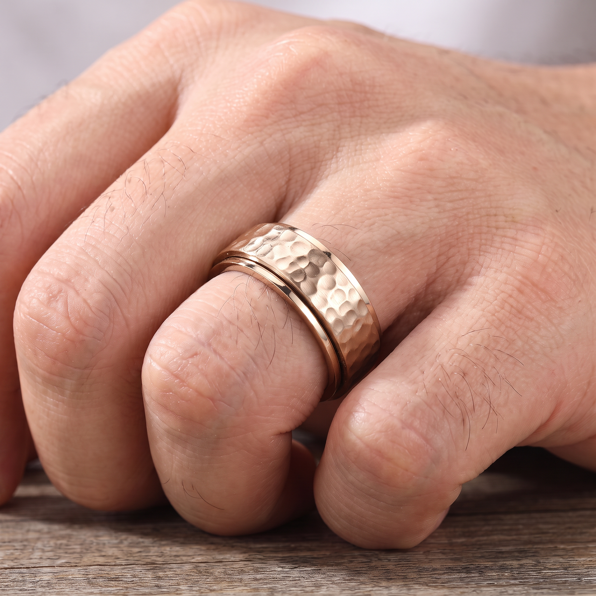 Close up of a man's hand wearing The Orbit rose spinner ring