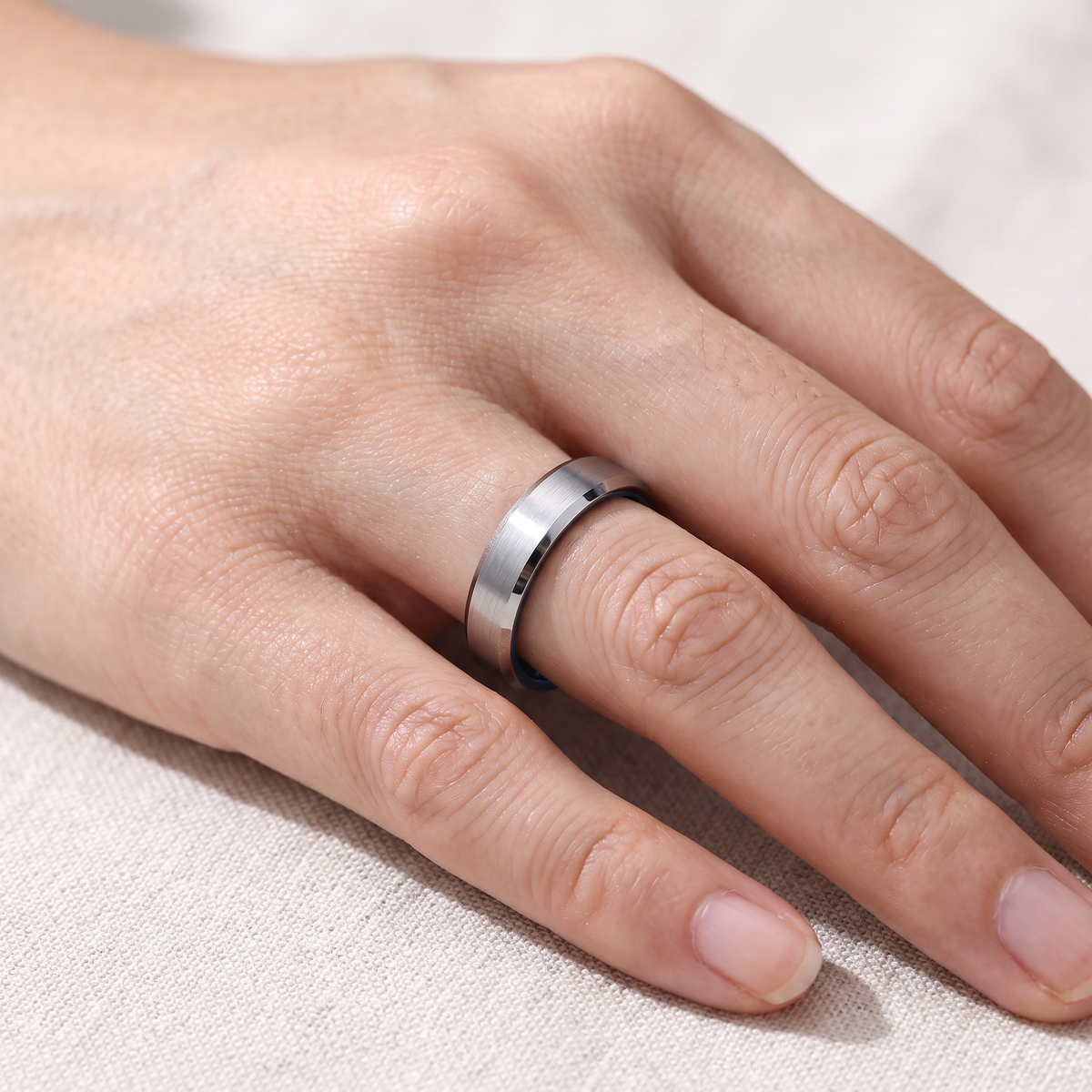 Close up of a woman's hand wearing The Halcyon slim silver tungsten ring with a blue inside