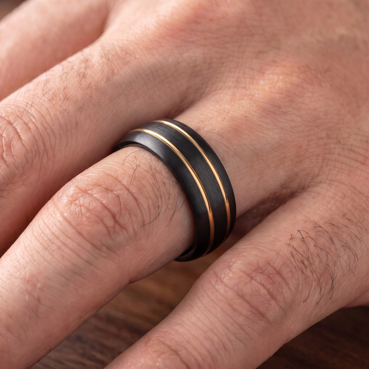 Close up of a man's hand wearing The Riptide black tungsten ring with a double gold line inlay