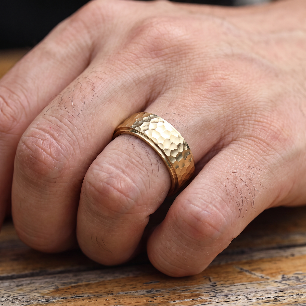 Close up of a man's hand wearing The Crater gold hammered ring