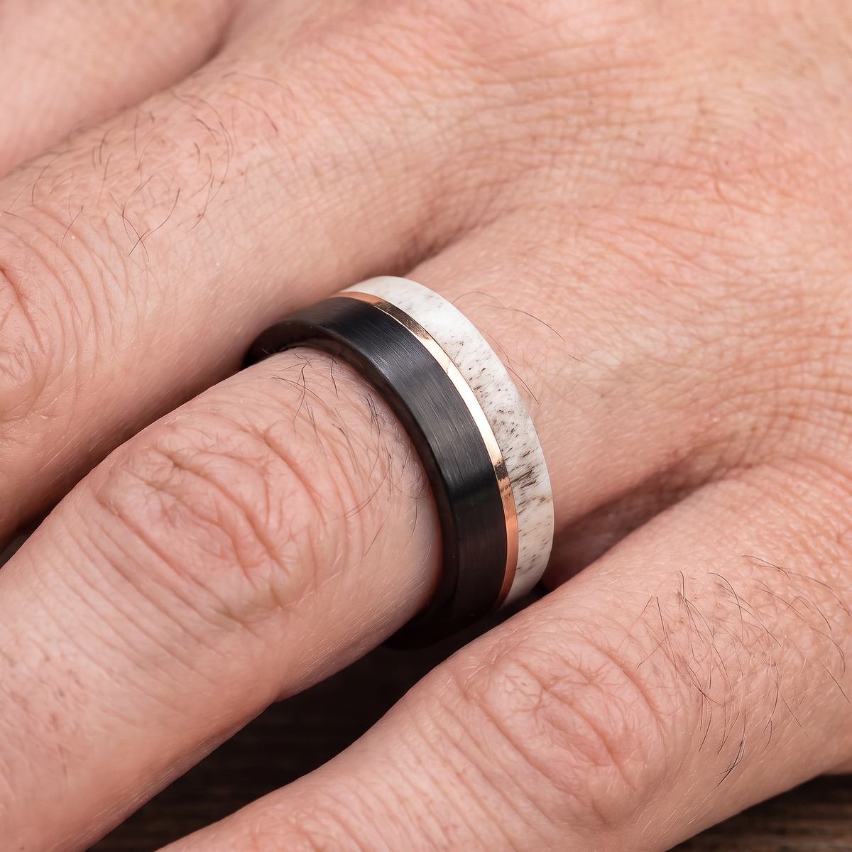 Close up of a man's hand wearing The Stag tungsten ring with a deer antler inlay