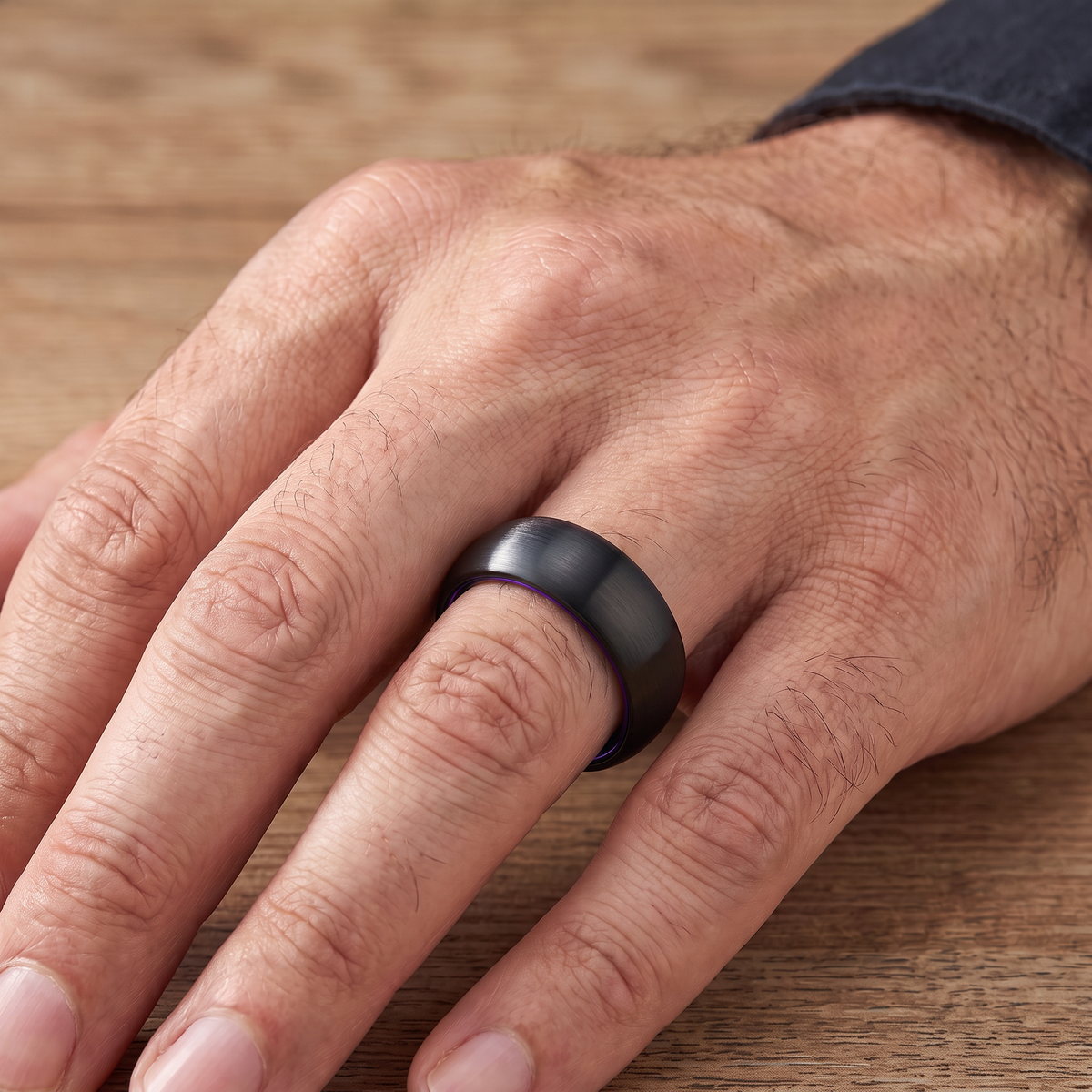 Close up of a man's hand wearing The Lantern brushed black tungsten ring with a purple aluminum interior