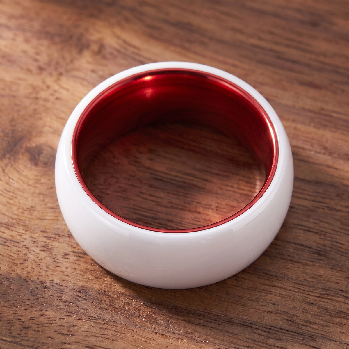 The Prism white ceramic ring lying flat showing the red interior