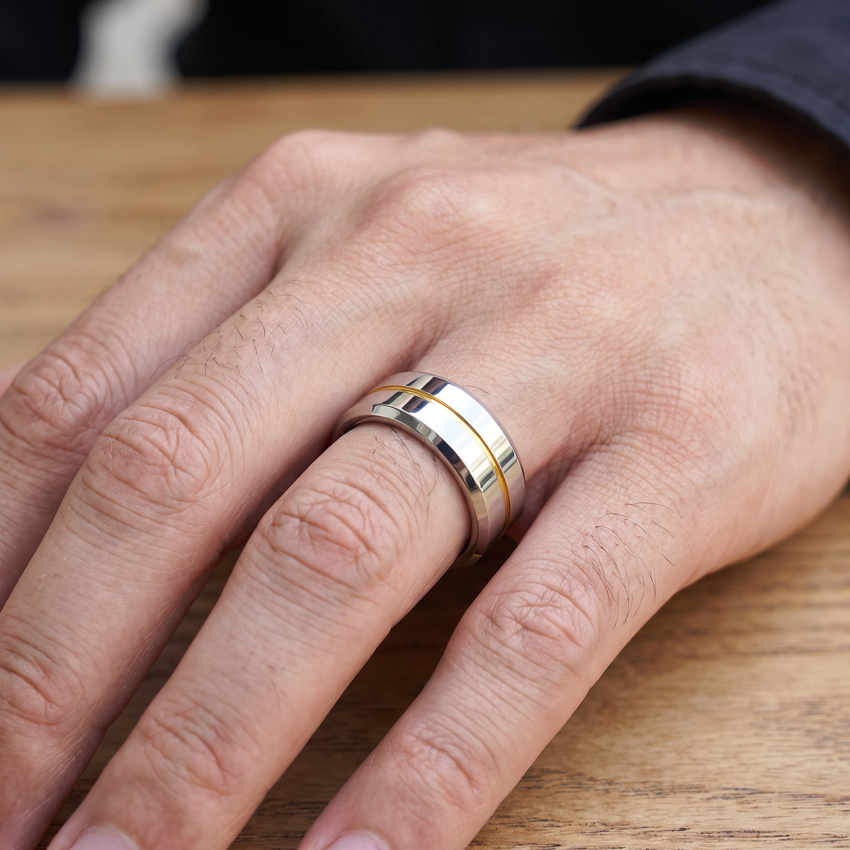 Close up of a man's hand wearing The Meridian tungsten ring with a yellow groove line
