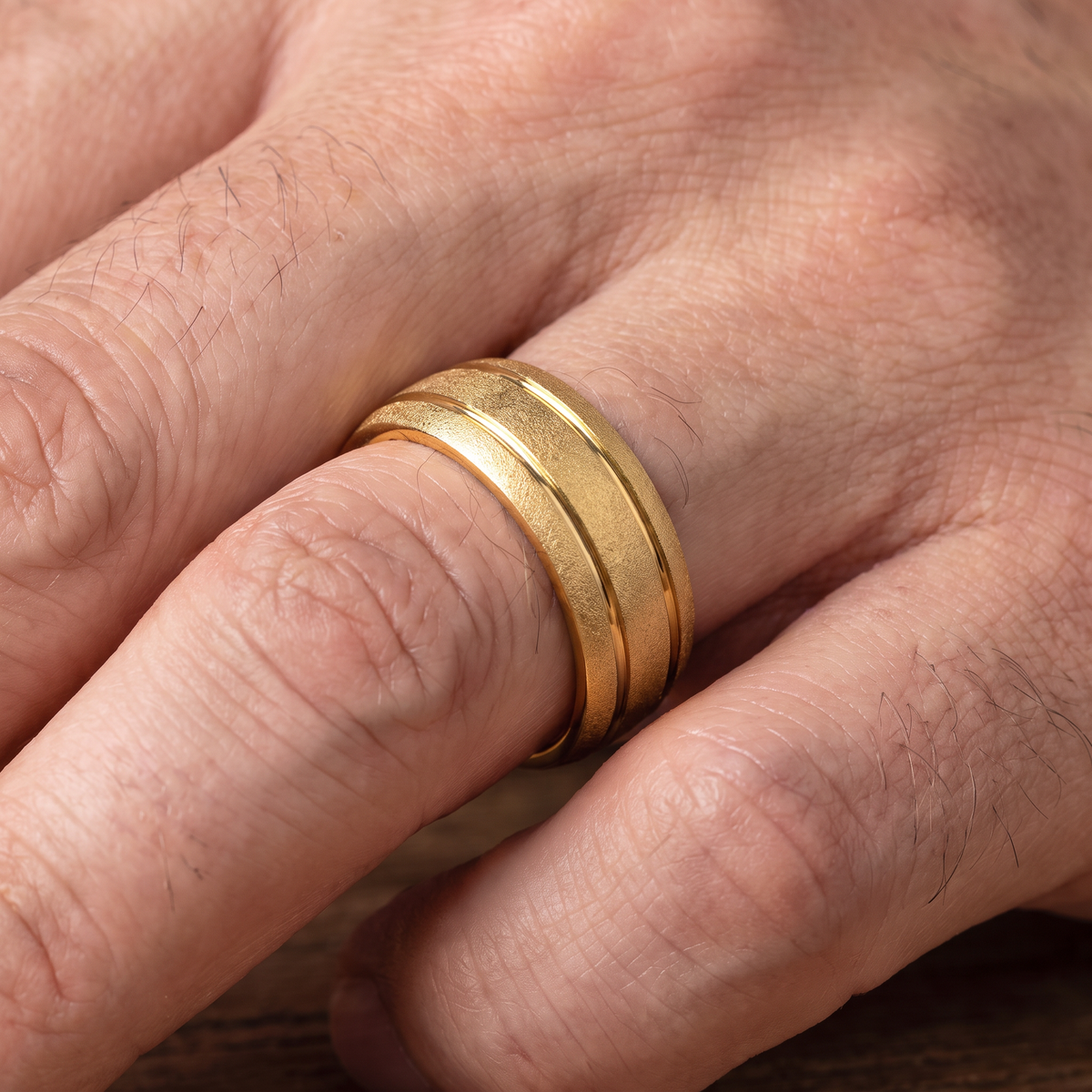 Close up of a man's hand wearing The Granite gold sandblasted tungsten ring