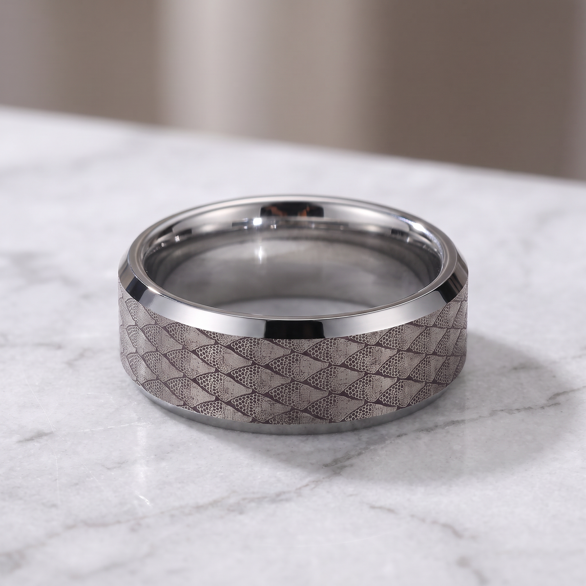 The Serpentine tungsten ring with a silver interior lying flat on a light grey marble surface