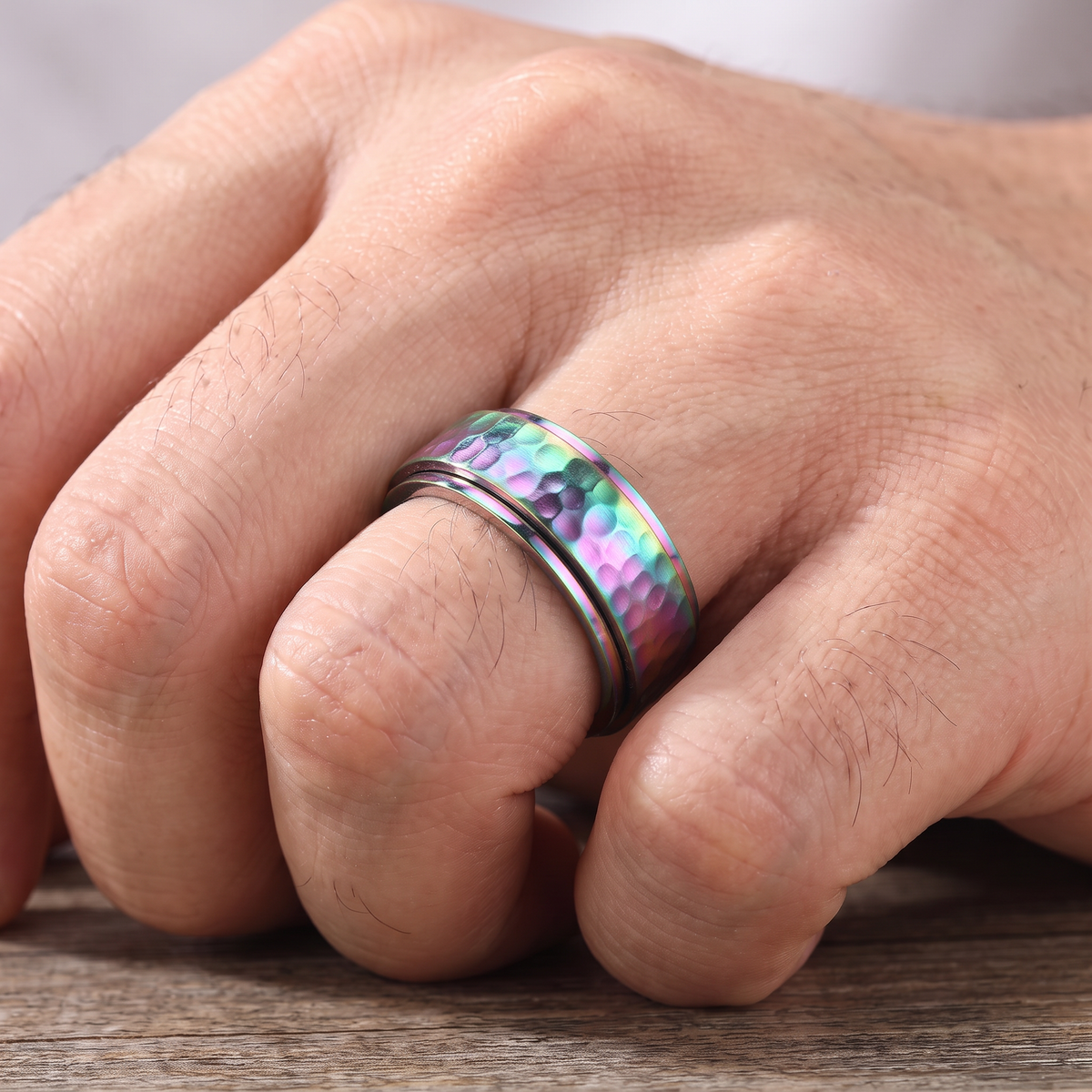 Close up of a man's hand wearing The Orbit rainbow spinner ring