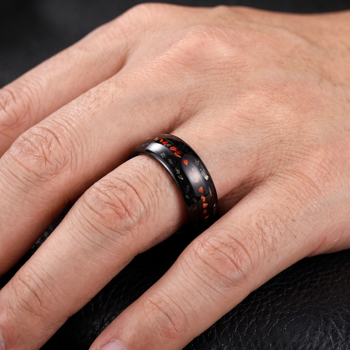 Man's hand wearing the domed black tungsten ring with dinosaur bone inlay