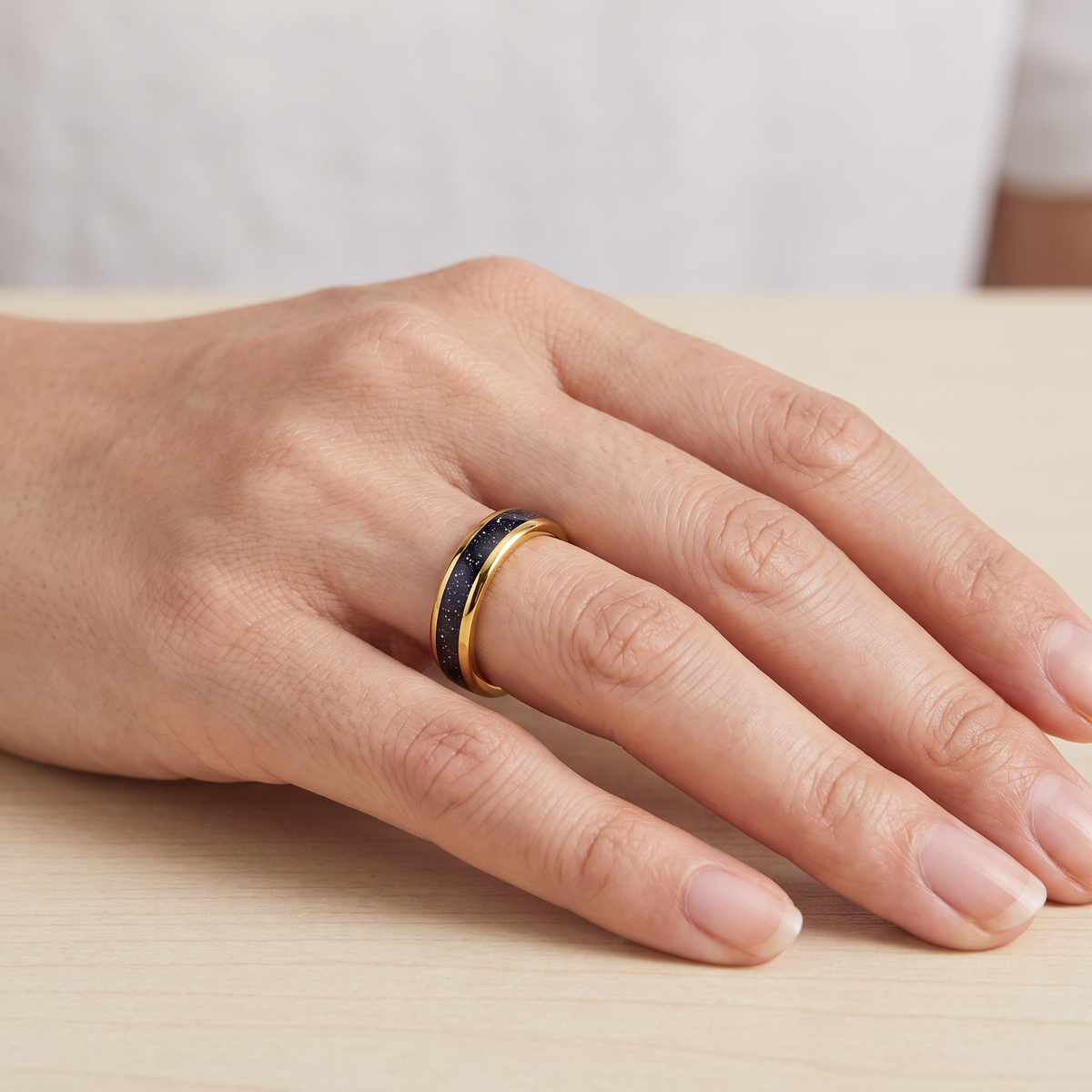 Close up of a woman's hand wearing The Vega gold color tungsten ring with a galaxy opal inlay