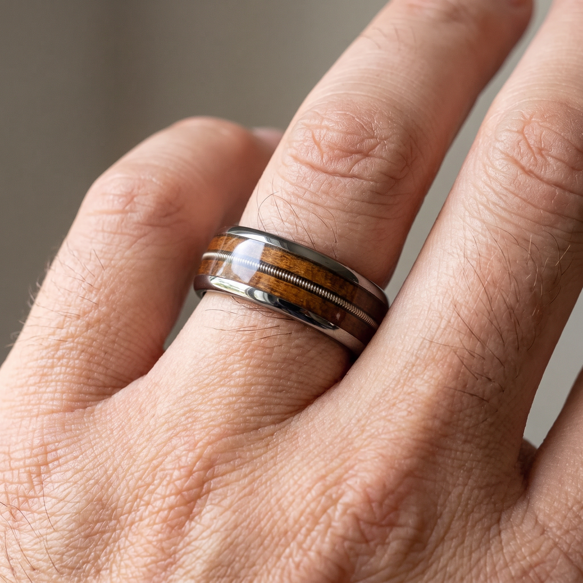 Close-up of a man's hand wearing The Roadhouse domed tungsten ring with whiskey barrel wood inlay