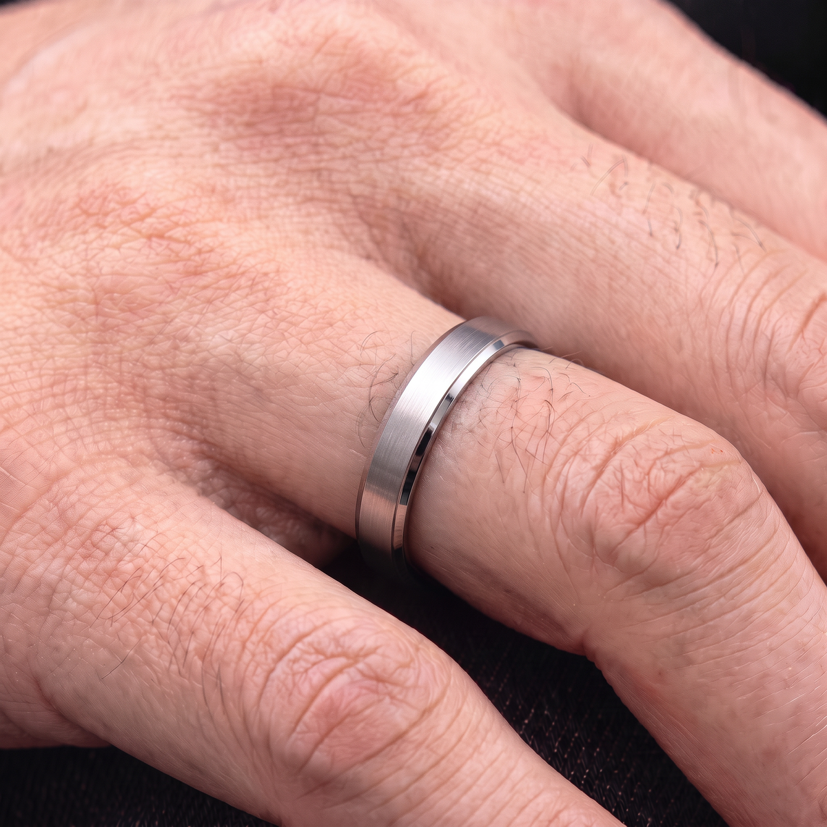 Close up of a man's hand wearing The Fathom 4mm slim silver tungsten ring