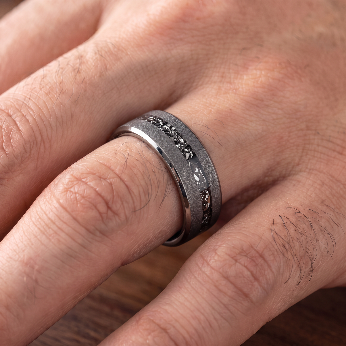 Close up of a man's hand wearing The Shard tungsten ring with a crushed zircon inlay