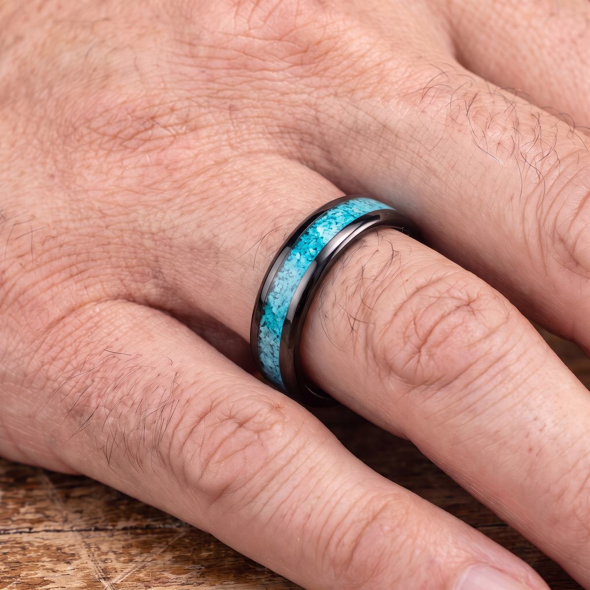 The Lagoon black tungsten ring with turquoise inlay worn on a man's hand