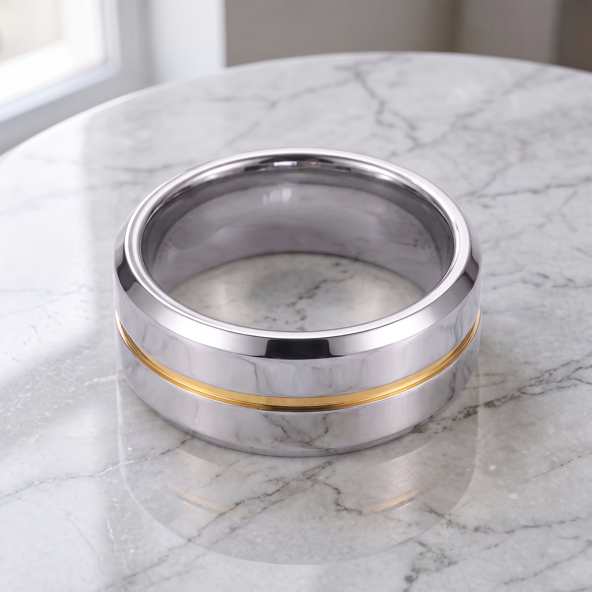 The Meridian tungsten ring with a yellow groove line lying flat on a white marble surface