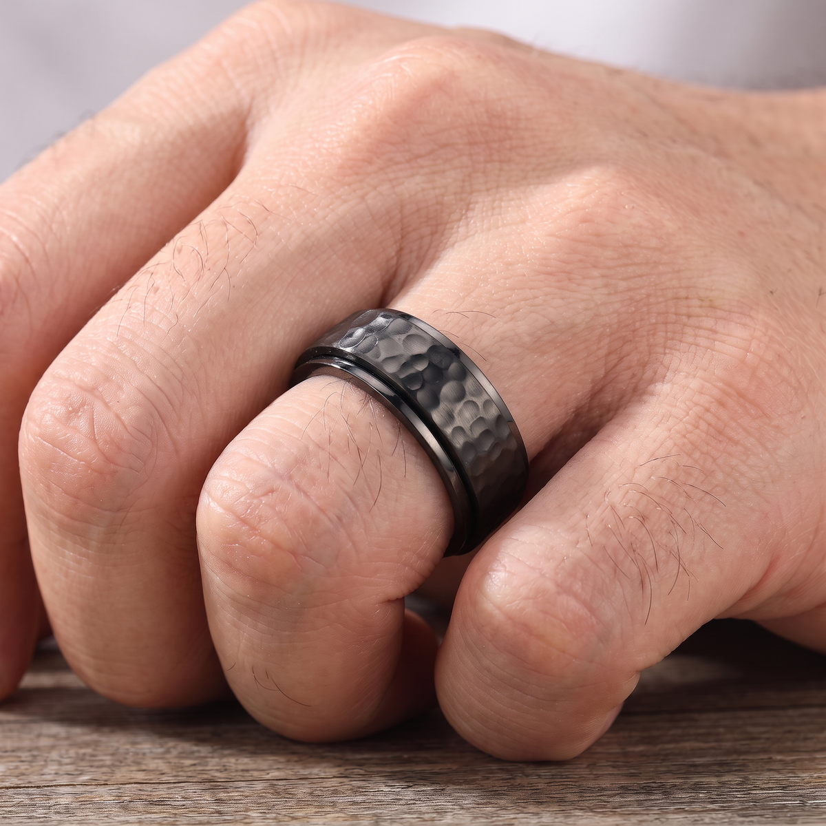 Close up of a man's hand wearing The Orbit black spinner ring