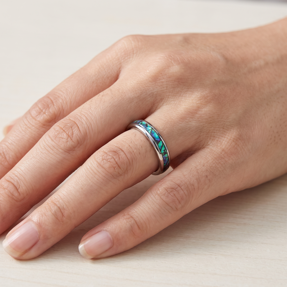 Close up of a woman's hand wearing The Iris silver color tungsten ring with an abalone shell inlay