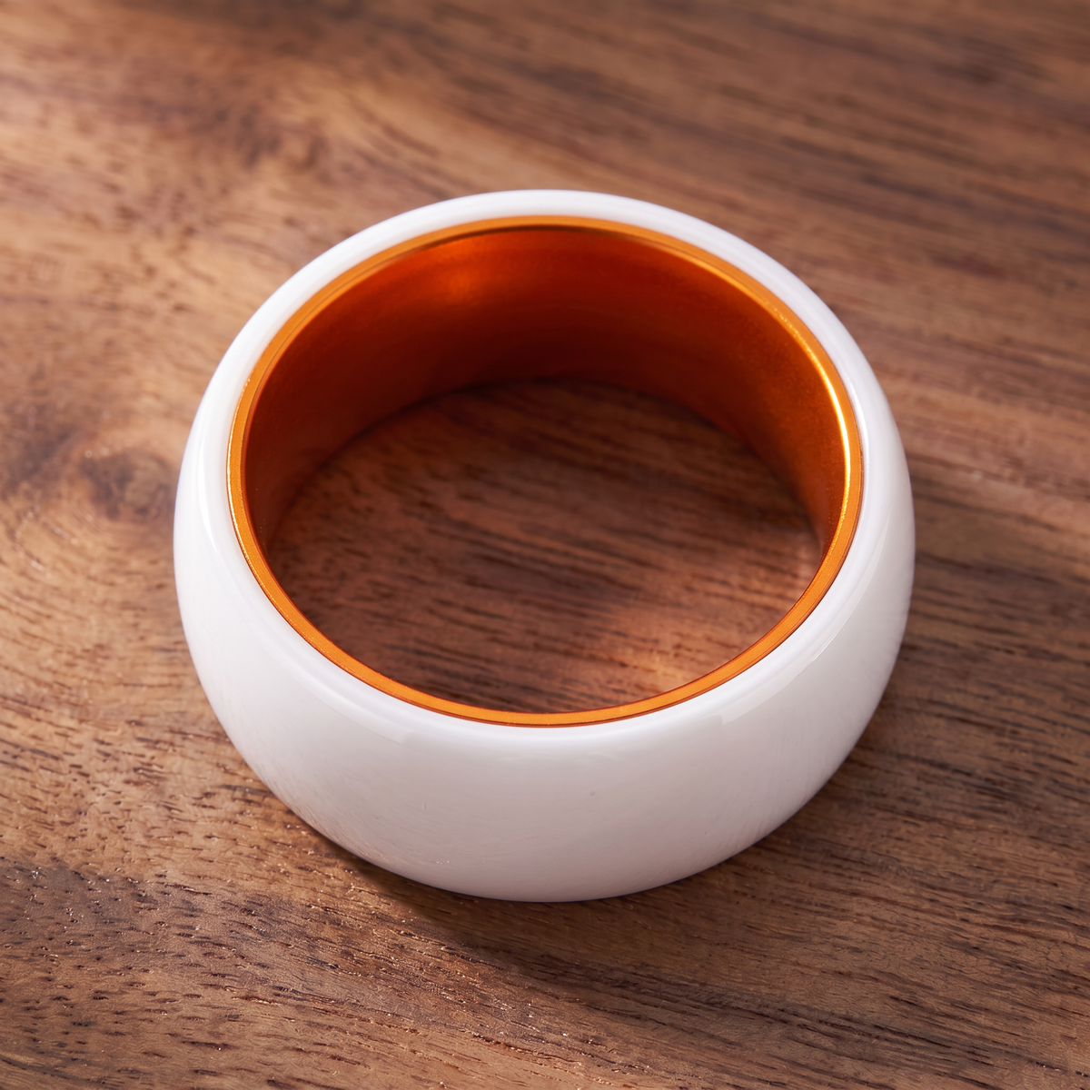 The Prism white ceramic ring lying flat showing the orange interior