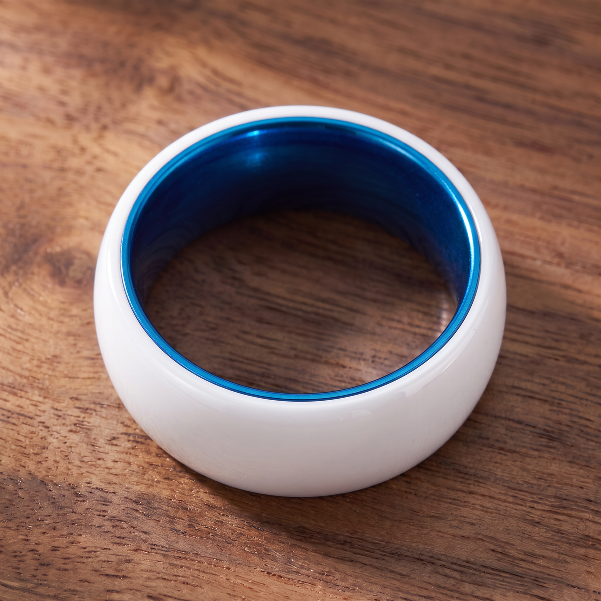 The Prism white ceramic ring lying flat showing the blue interior