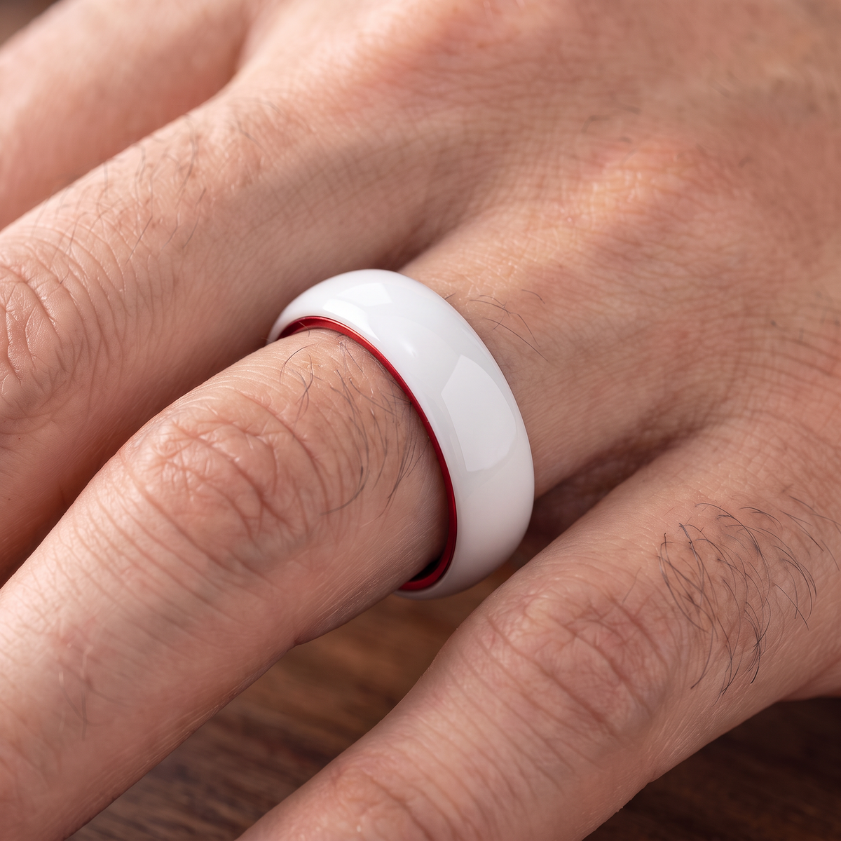 The Prism white ceramic ring with red interior worn on a hand