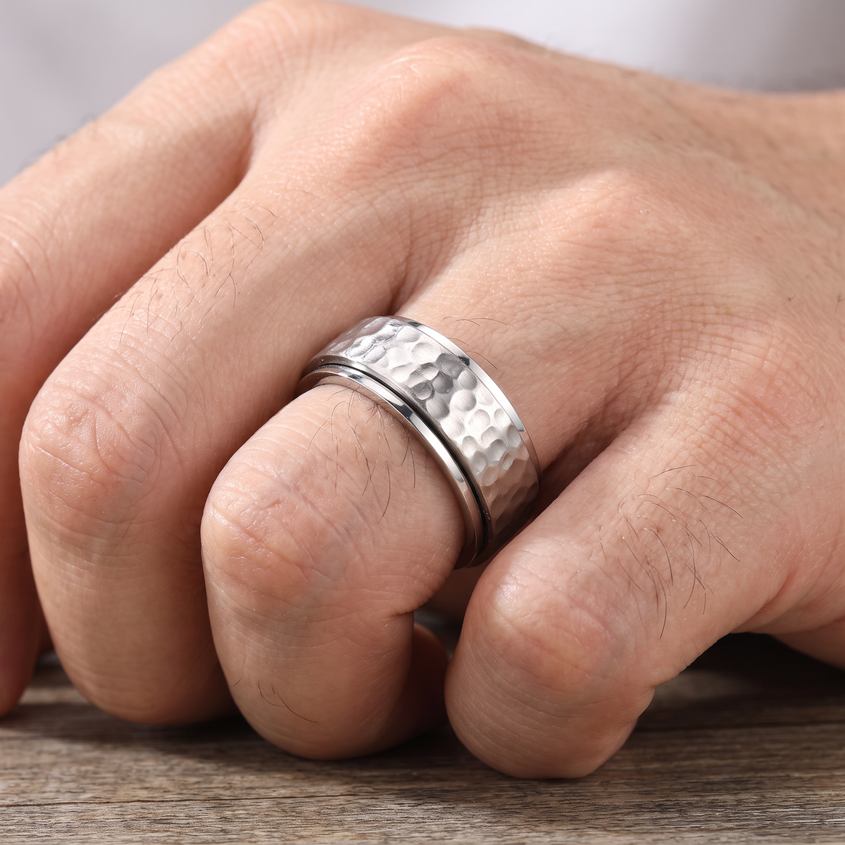 Close up of a man's hand wearing The Orbit silver spinner ring